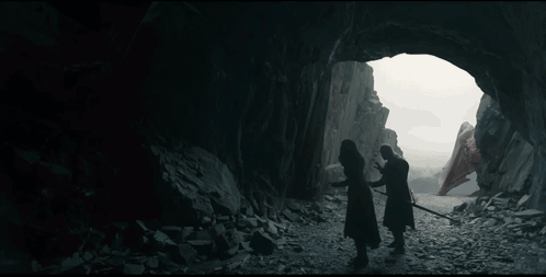 A Man With Long White Hair Is Standing In Front Of A Rock Wall And Looking At The Camera . GIF