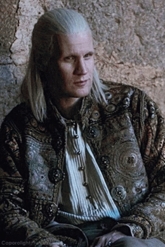 a man with long white hair is wearing a jacket with buttons
