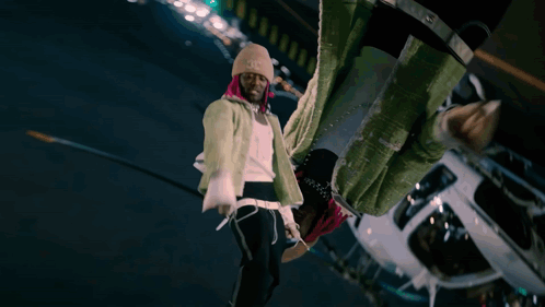 A Man With Pink Hair And A Beanie Stands In Front Of A White Helicopter GIF