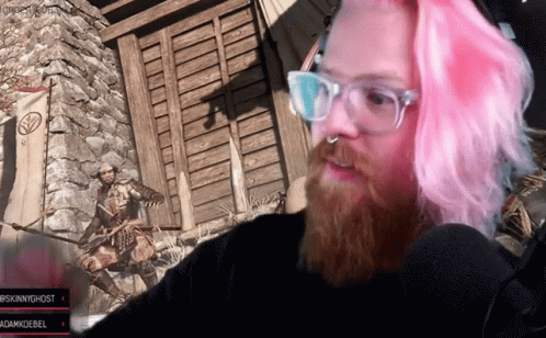 A Man With Pink Hair And Glasses Looks At The Camera GIF