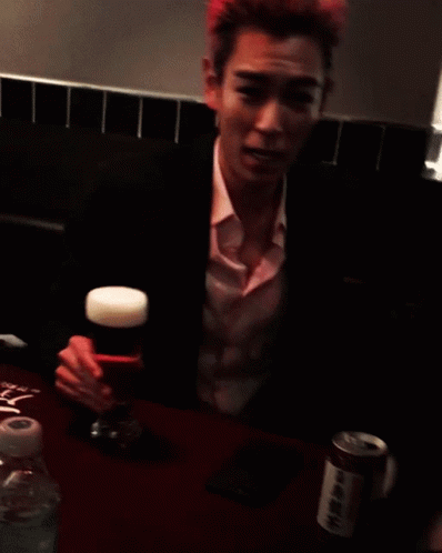 a man with pink hair holds a glass of beer in his hand