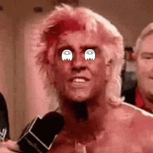 A Man With Pink Hair Is Talking Into A Microphone And Has Ghosts In His Eyes . GIF