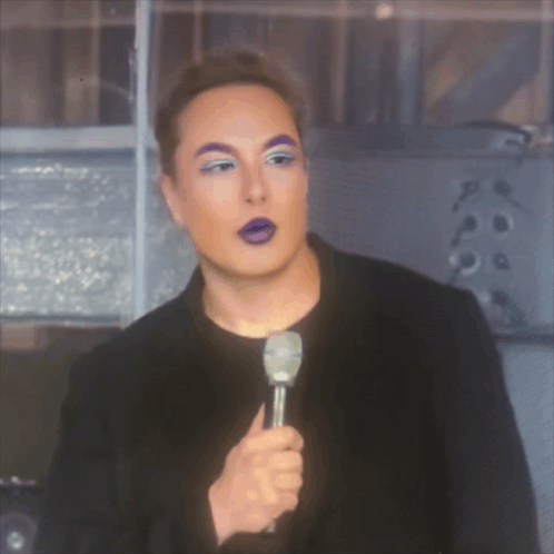 a man with purple eyebrows is holding a microphone in his hand