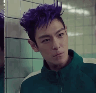 A Man With Purple Hair Is Standing In Front Of A Mirror . GIF