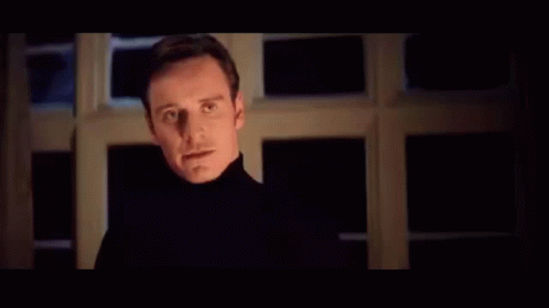A Man With Red Eyes Is Standing In Front Of A Sign That Says Perfection In Blue Letters . GIF
