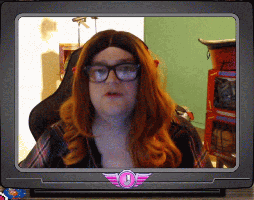 A Man With Red Hair And Glasses Is On A Tv Screen With A Pink Emblem With An Exclamation Point GIF