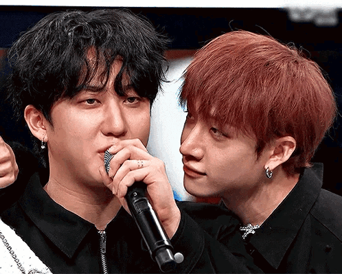 A Man With Red Hair Is Holding A Microphone Next To Another Man GIF