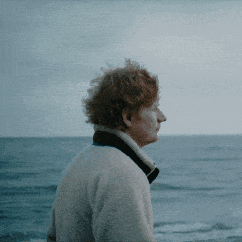 A Man With Red Hair Is Looking Out Over The Ocean GIF
