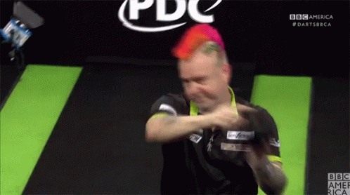 A Man With Red Hair Is Playing Darts In Front Of A Bbc America Logo GIF
