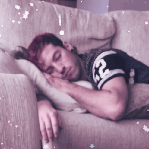 A Man With Red Hair Is Sleeping On A Couch With A Shirt That Says Rc On It GIF