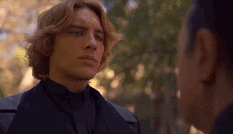 A Man With Red Hair Is Standing Next To A Woman In A Black Suit . GIF