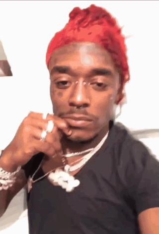 A Man With Red Hair Is Wearing A Black Shirt And A Silver Necklace GIF