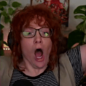 A Man With Red Hair Wearing Glasses And Headphones Is Making A Surprised Face . GIF
