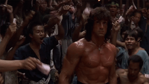 A Man With Red Paint On His Body Is Standing In Front Of A Crowd GIF