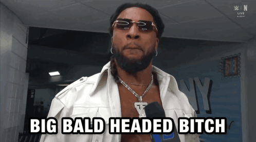 A Man With Sunglasses And A Necklace Says Big Bald Headed Bitch GIF