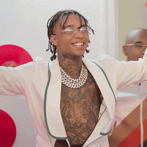 A Man With Tattoos On His Chest Is Wearing Glasses GIF