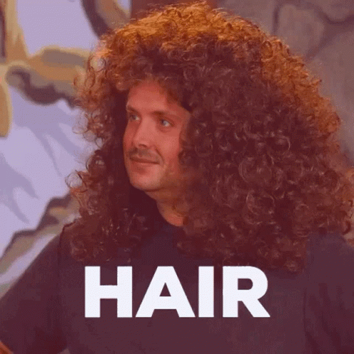 A Man With Very Long Curly Hair Is Standing In Front Of The Word Hair . GIF