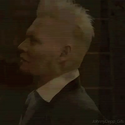 A Man With White Hair Is Wearing A Black Suit And Tie . GIF