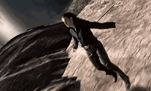 A Man With Wings Is Flying Through The Air Over A Rock . GIF