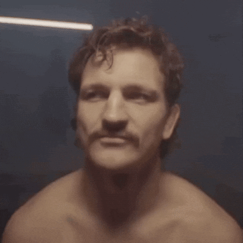 A Man Without A Shirt Has A Mustache And Looks At The Camera GIF