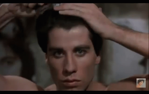 A Man Without A Shirt Is Brushing His Hair In Front Of A Mirror GIF