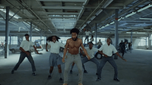A Man Without A Shirt Is Dancing With A Group Of People In White Shirts GIF