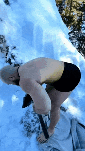 A Man Without A Shirt Is Digging In The Snow With An Axe GIF