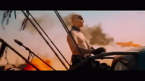 A Man Without A Shirt Is Driving A Car Through A Desert . GIF