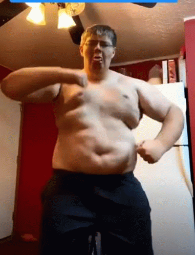A Man Without A Shirt Is Flexing His Muscles In A Kitchen . GIF