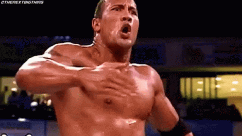 A Man Without A Shirt Is Holding His Chest In A Wrestling Ring . GIF