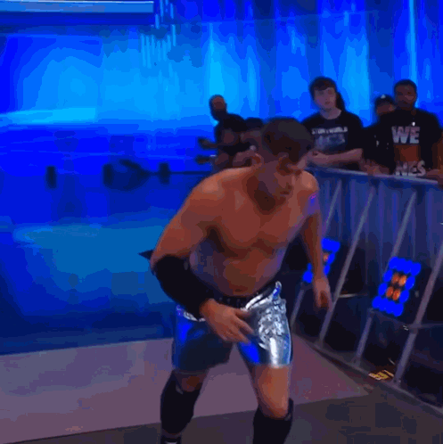 a man without a shirt is jumping in the air in front of a blue background