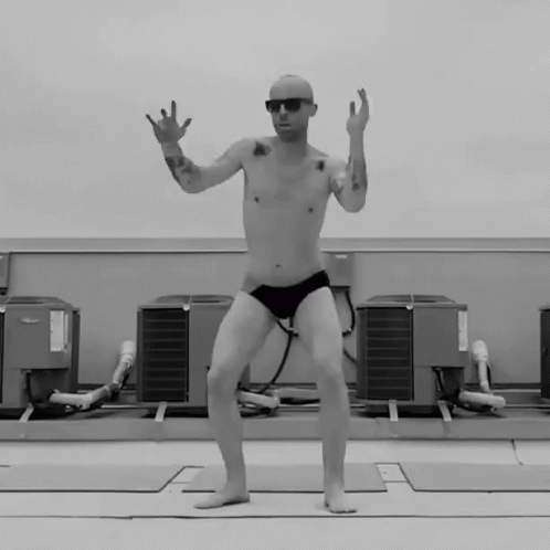 A Man Without A Shirt Is Jumping In The Air In Front Of A Bunch Of Air Conditioners GIF