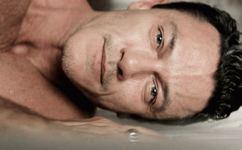 A Man Without A Shirt Is Laying In A Bathtub With His Eyes Closed GIF