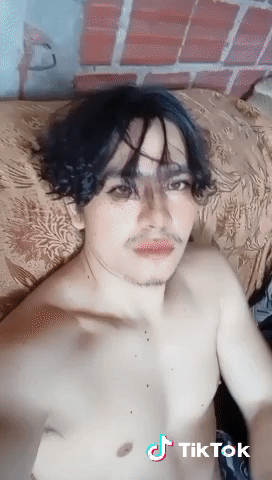 A Man Without A Shirt Is Laying On A Bed With A Tiktok Watermark GIF