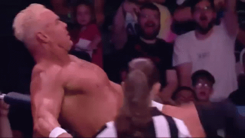 A Man Without A Shirt Is Laying On The Ground In Front Of A Crowd . GIF