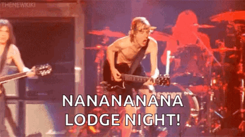 A Man Without A Shirt Is Playing A Guitar On A Stage In Front Of A Drummer . GIF