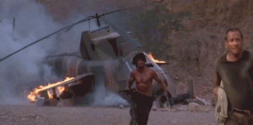 A Man Without A Shirt Is Running In Front Of A Large Explosion GIF