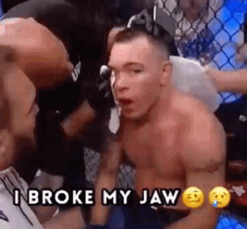 A Man Without A Shirt Is Sitting In A Boxing Ring With Another Man And Says `` I Broke My Jaw '' . GIF