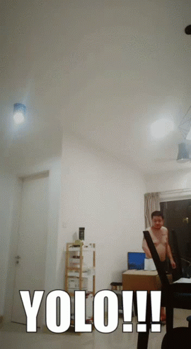 A Man Without A Shirt Is Standing In A Living Room With The Words Yolo Written In White GIF