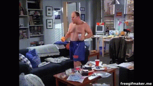 A Man Without A Shirt Is Standing In A Messy Room GIF