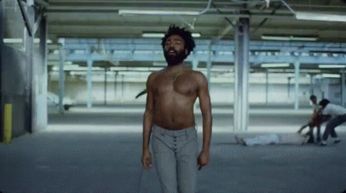 A Man Without A Shirt Is Standing In A Warehouse GIF