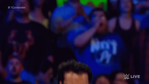 A Man Without A Shirt Is Standing In A Wrestling Ring With A Crowd Watching . GIF