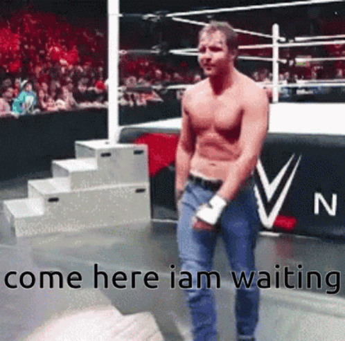 A Man Without A Shirt Is Standing In A Wrestling Ring With The Words Come Here I Am Waiting . GIF
