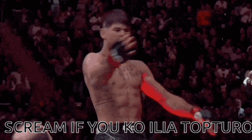 A Man Without A Shirt Is Standing In Front Of A Crowd And Screaming . GIF