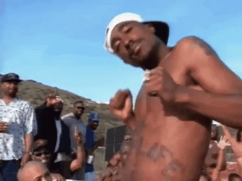 A Man Without A Shirt Is Standing In Front Of A Crowd . GIF
