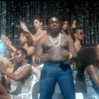 A Man Without A Shirt Is Standing In Front Of A Crowd Of Women . GIF