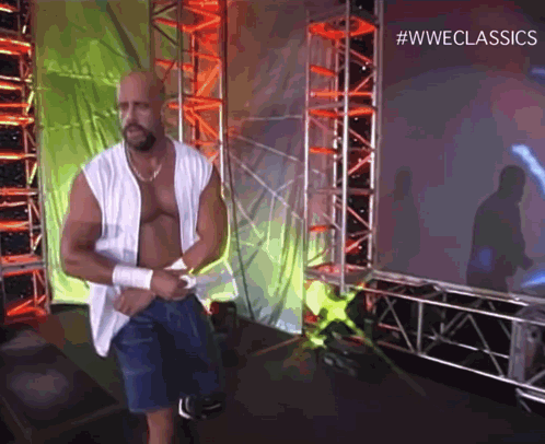 a man without a shirt is standing in front of a screen that says #wweclassics .