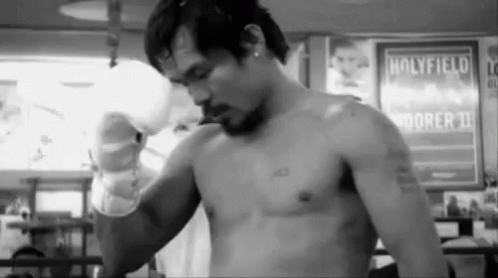A Man Without A Shirt Is Standing In Front Of A Sign That Says Holyfield On It . GIF