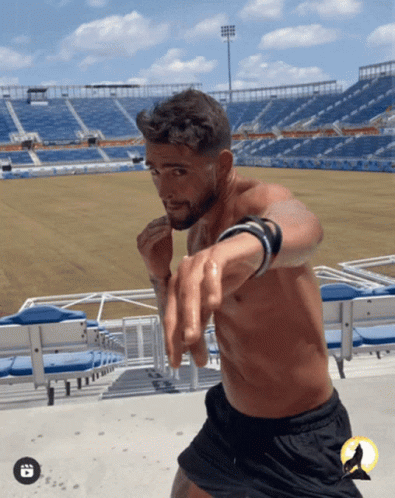 A Man Without A Shirt Is Standing In Front Of A Stadium That Says ' Florida ' On It GIF