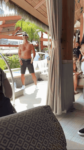 A Man Without A Shirt Is Standing In Front Of A Swimming Pool GIF